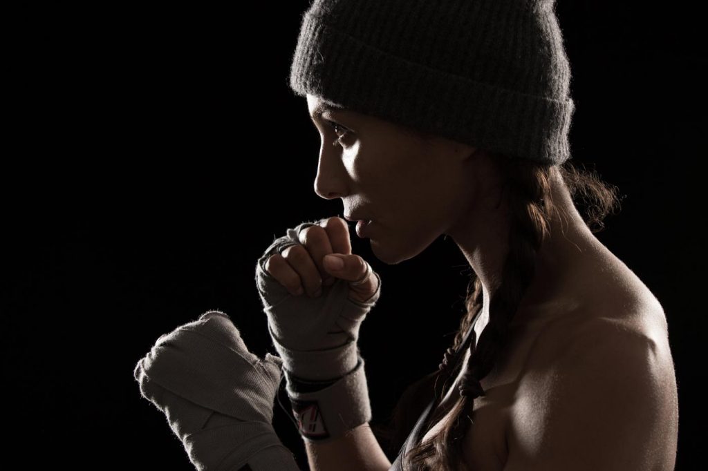 An edge lit picture of Marem Hassler in hand wraps preparing to box by sports portrait photographer Nick Reid.